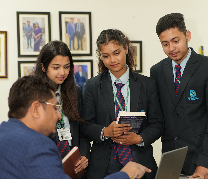 Students and a teacher discussing around a laptop