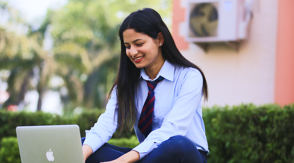Student using a laptop and smiling
